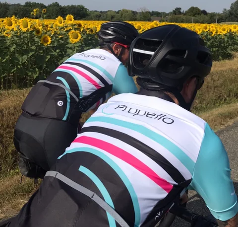 A rear view two cyclists with Propello branding on their shirts