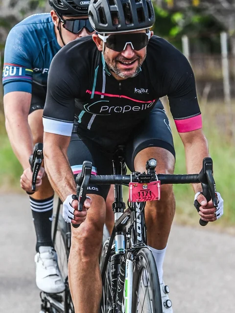 front side of the 3 cyclists racing on a country road